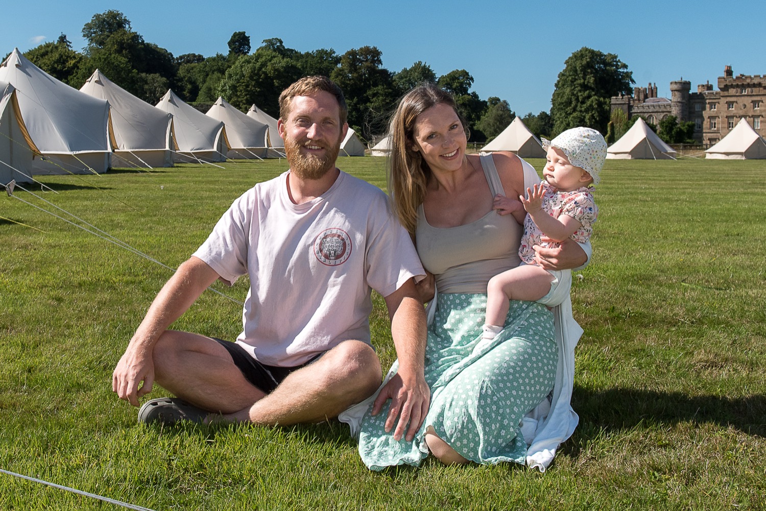 Max, Ruby and their daughter in front of a row of bell tents at Hawarden Castle