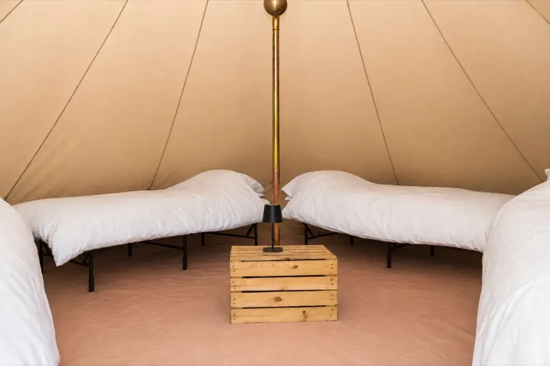 Essentials bell tent with apple crate table and camping light, real beds added as an extra