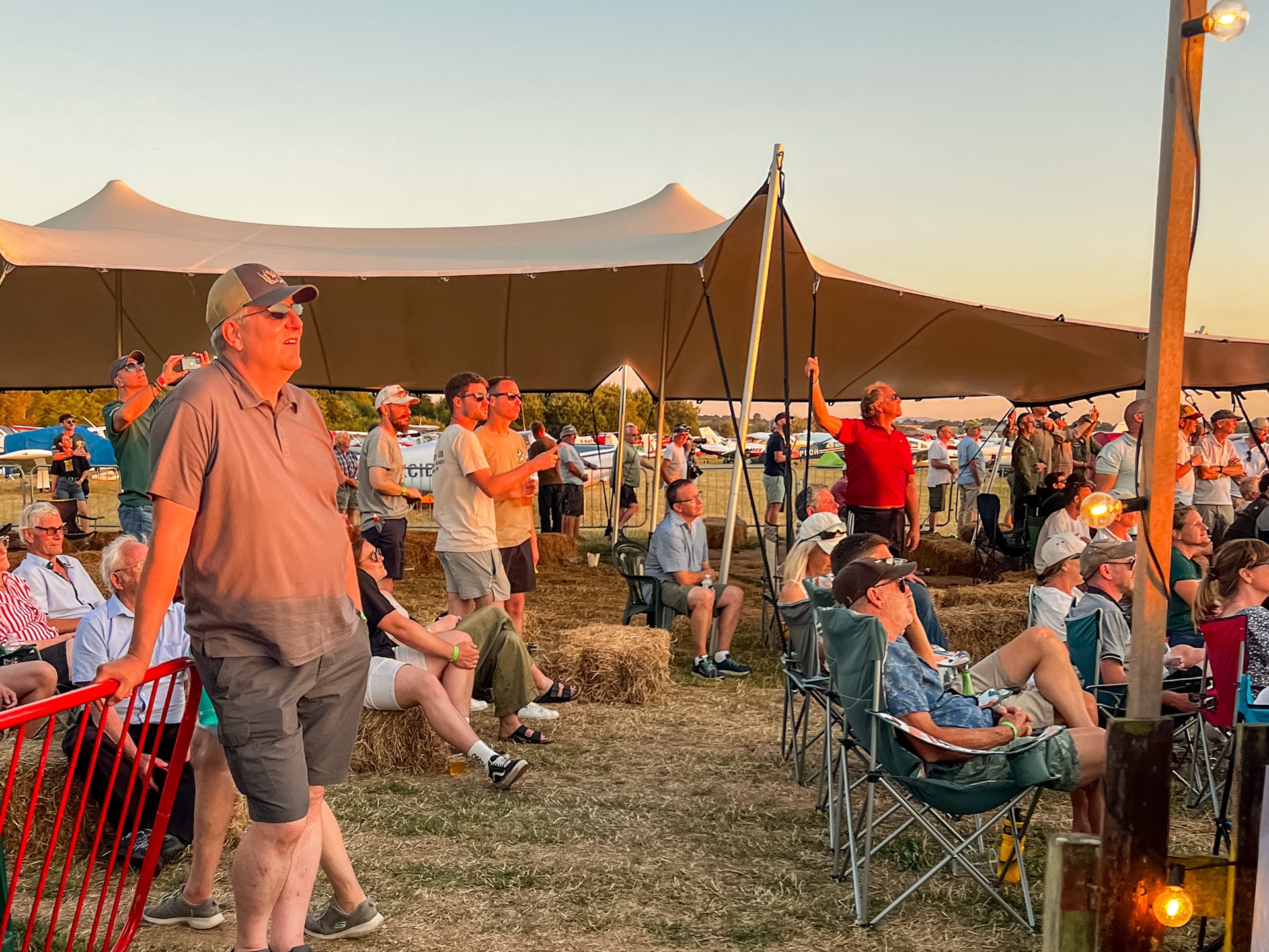 Crowd watching an air display from under a stretch tent at golden hour