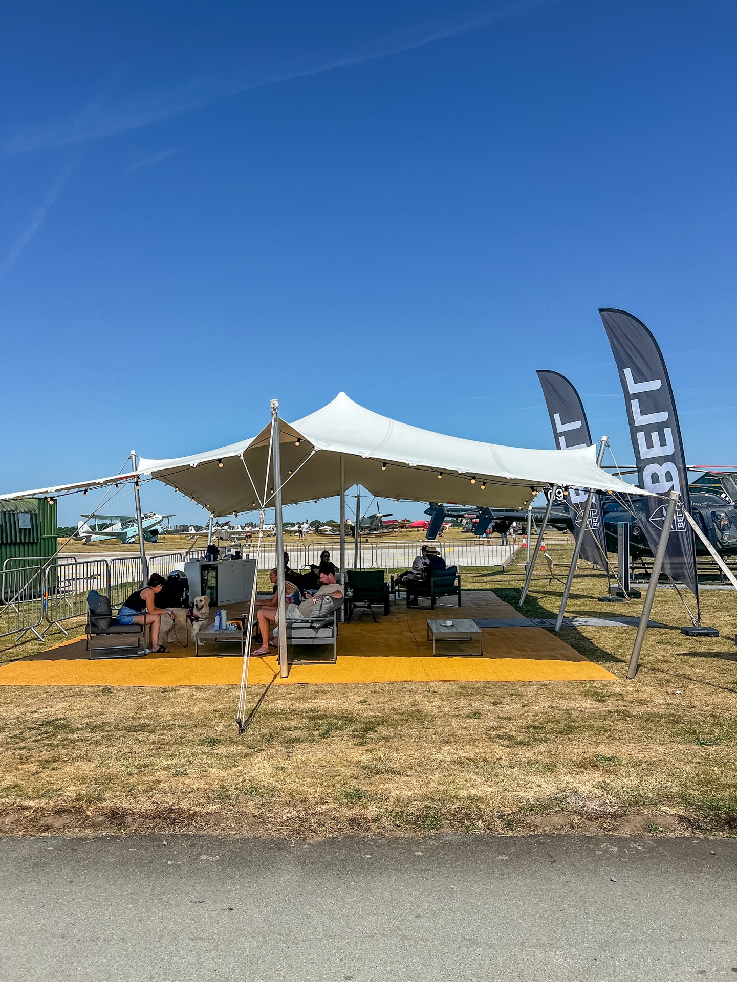 Stretch tent set up as an event lounge with sofas beside the flightline