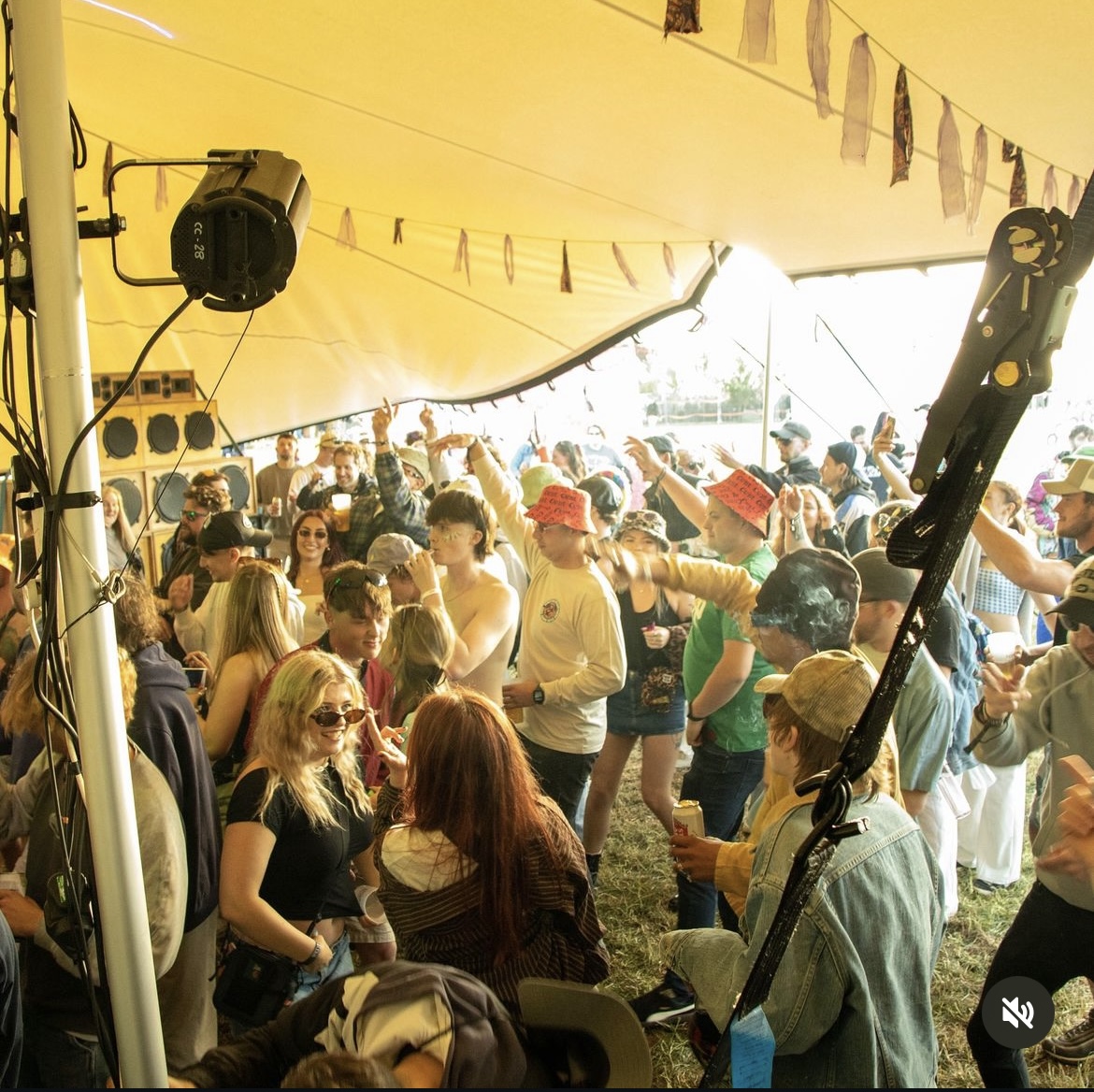 A packed crowd under a stretch tent at a festival