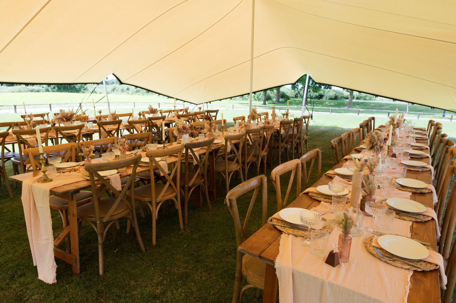 Wedding breakfast on long banquet tables under a stretch tent