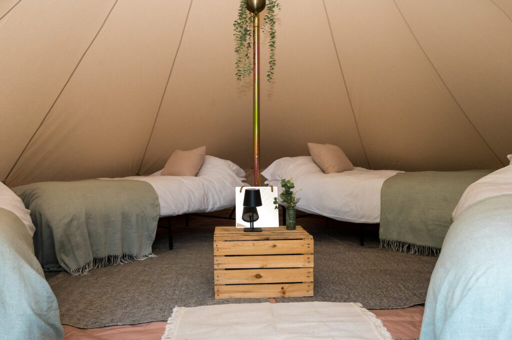 Four single beds made up inside a 5m bell tent for a wedding