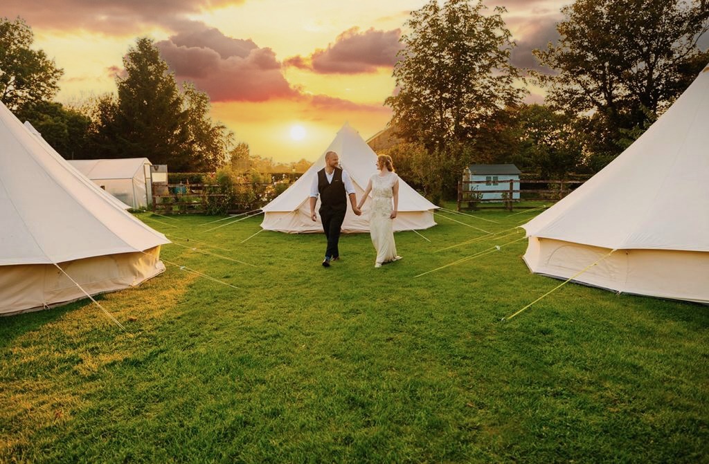 wedding couple in front of glamping tent village