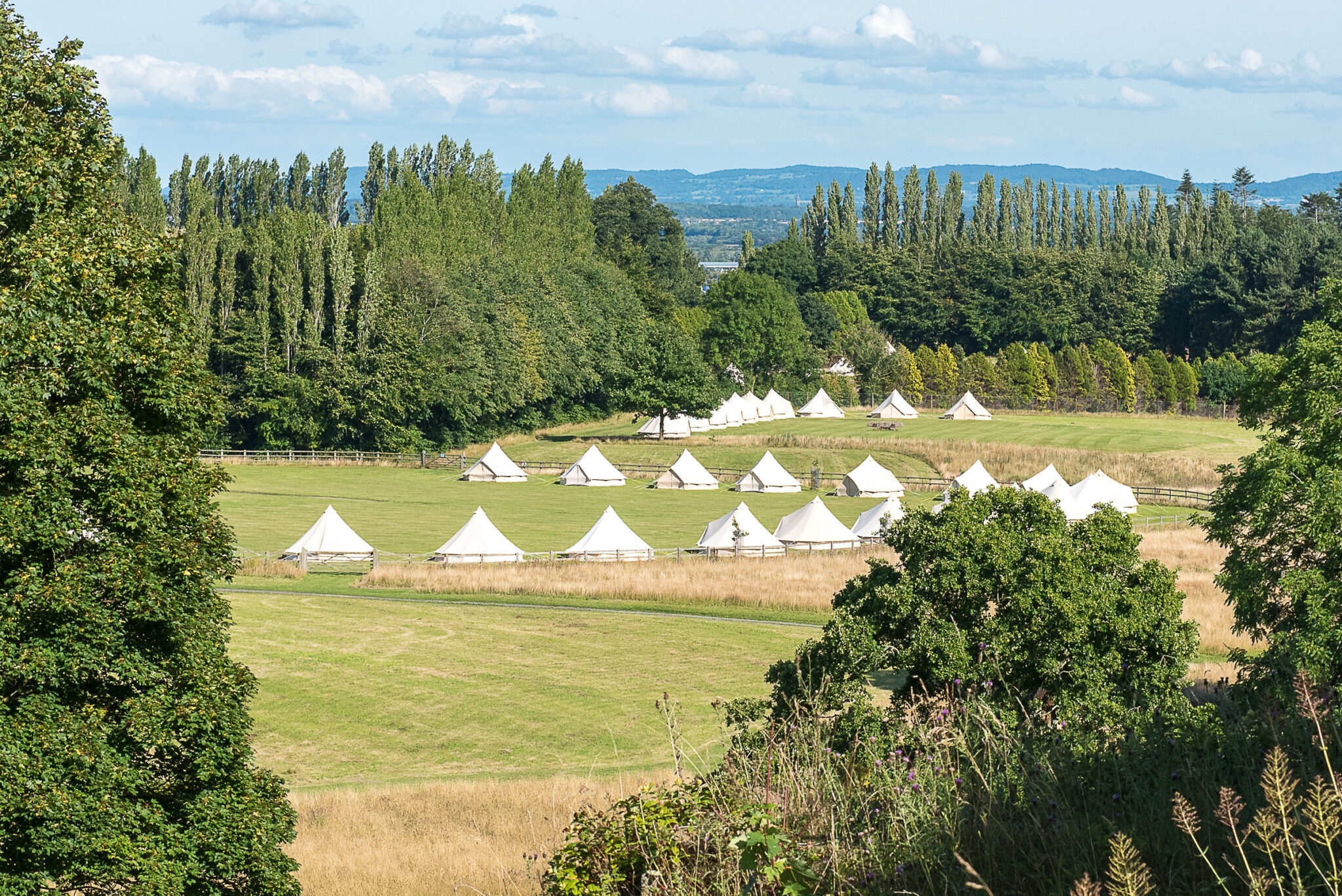 Bell tent village laid out across parkland at an event