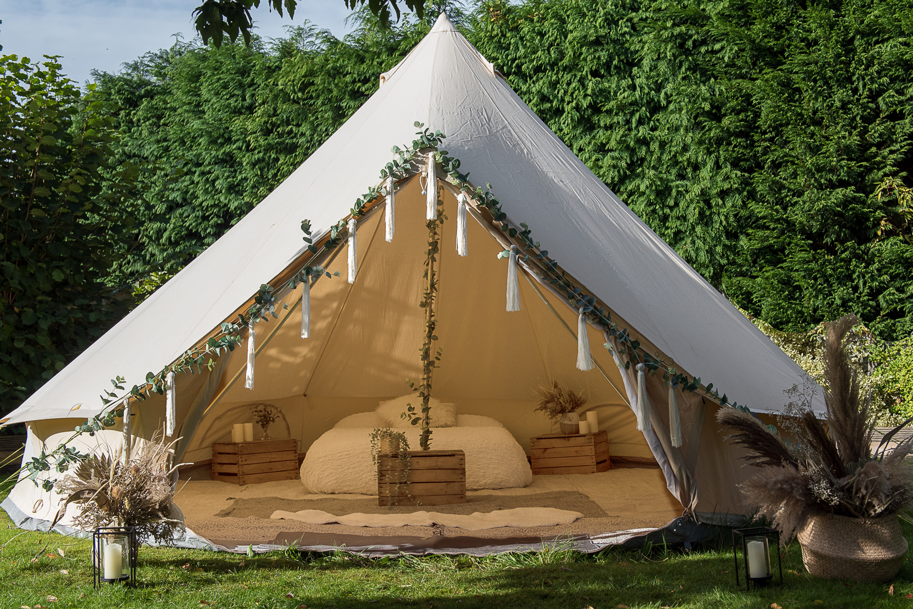 Bridal bell tent dressed with eucalyptus and tassels, double bed made up inside