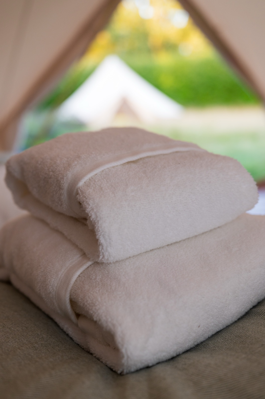 Fresh towels folded on a bed inside a bell tent